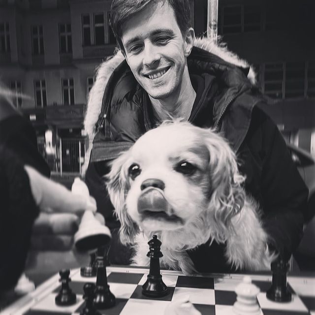 A man and his dog leaning over the chess board